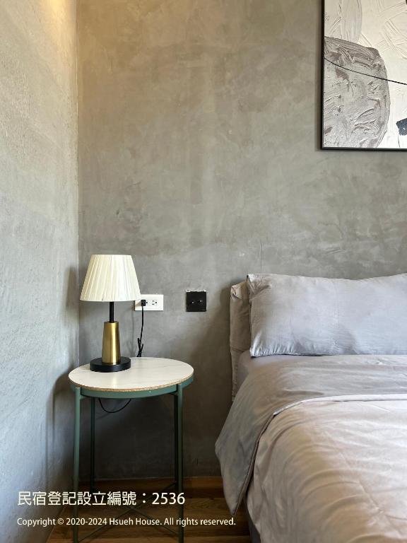 a bedroom with a bed and a table with a lamp at hsueh_house in Yilan City