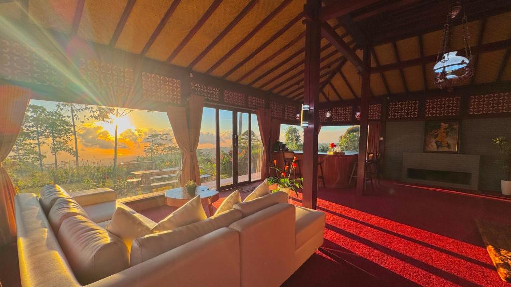 a living room with a white couch and windows at The Joglo Sekar Munduk in Pabean Buleleng