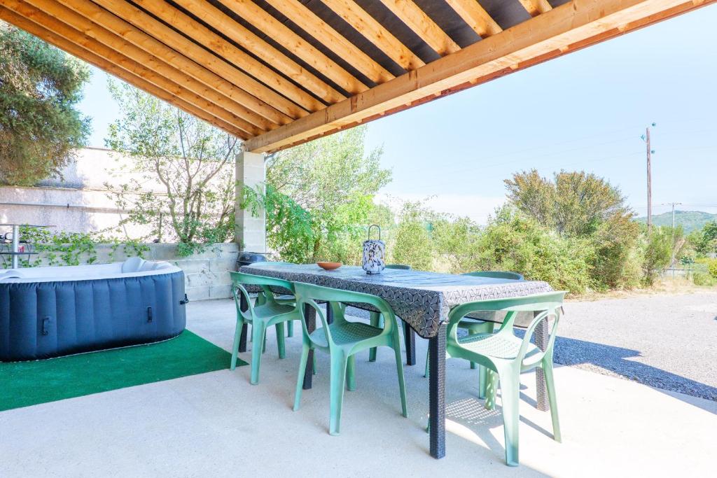 a patio table and chairs under a pergola at Le gecko avec jacuzzi in Saint-Germain