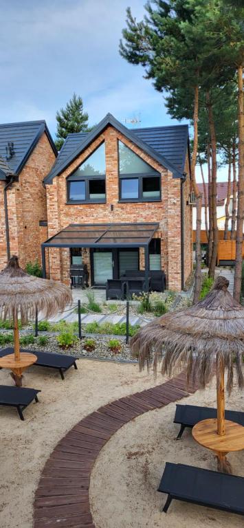 a house with two straw umbrellas in front of it at Sosnowy Szum Sauna 3 Wanny Spa in Jastrzębia Góra