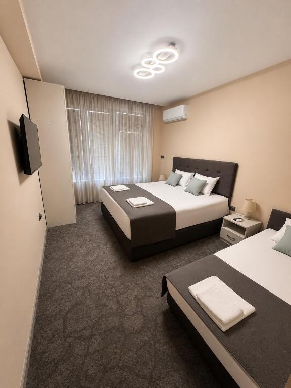 ein Hotelzimmer mit zwei Betten und einem Fernseher in der Unterkunft Hotel Ponti in Widin