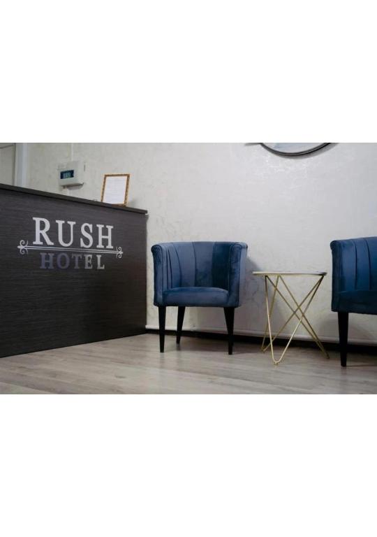 two blue chairs in a room with a hotel sign at Rush Hotel in Atyrau