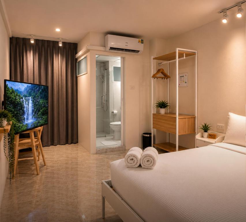 a bedroom with a bed and a tv and a bathroom at 95 Lodge in Bangkok