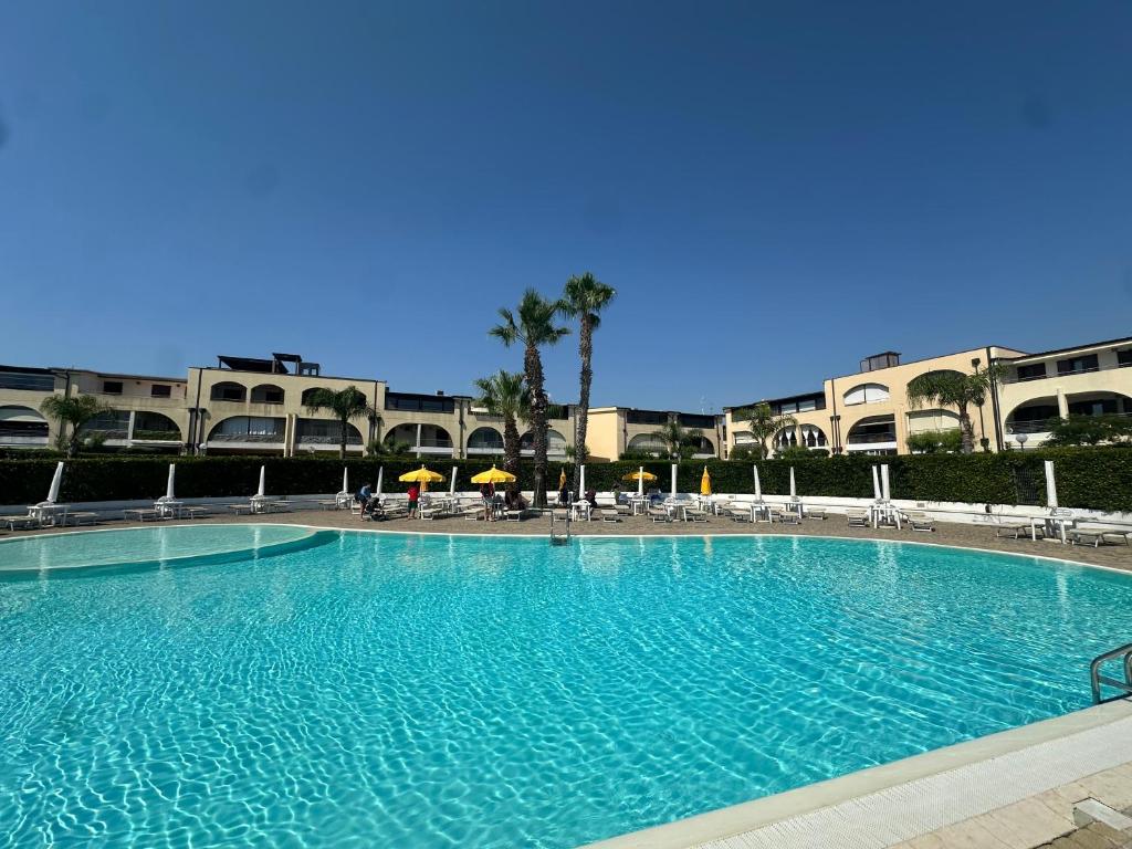 a large blue swimming pool with chairs and umbrellas at La CASA DI LUDO in Bernalda