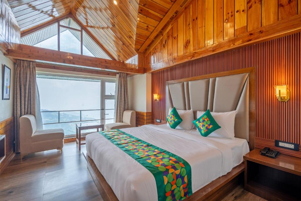 a bedroom with a large bed and a large window at Treebo Fagu Peaks in Shimla
