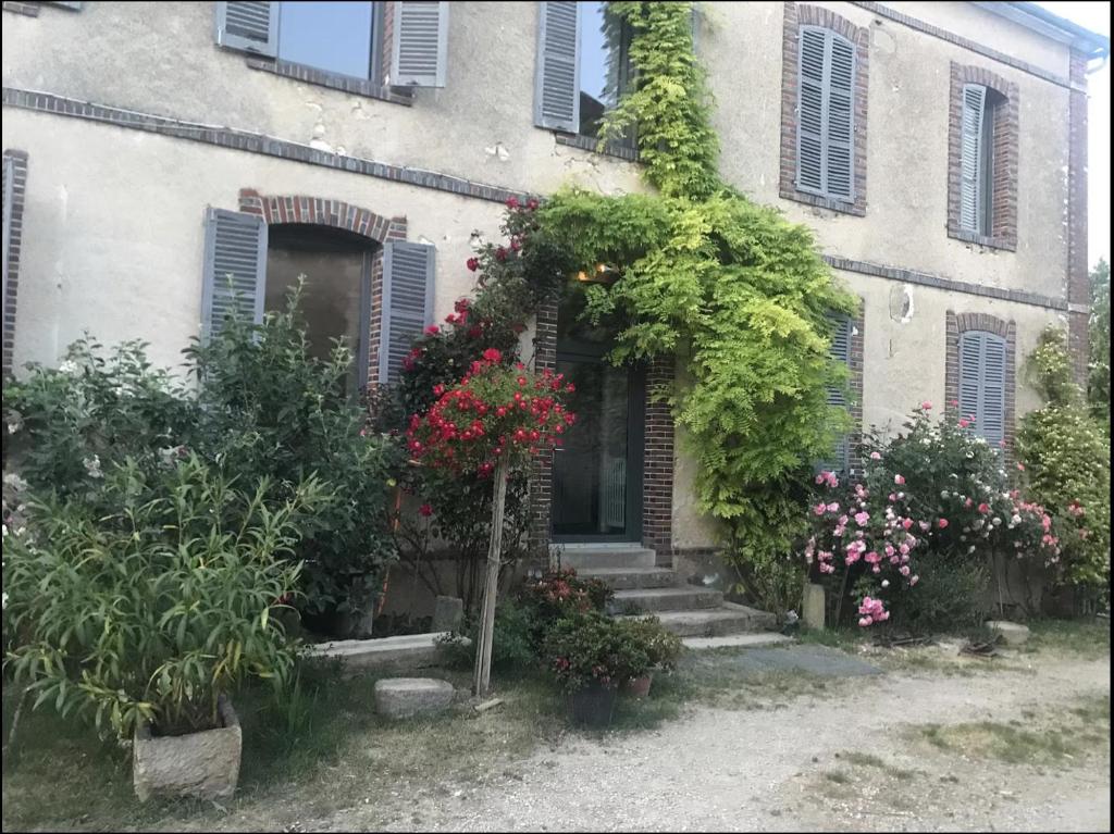 a house with flowers and plants in front of it at Grand corps de ferme à la rue Messire Etienne 89113 Neuilly Valravillon in Neuilly