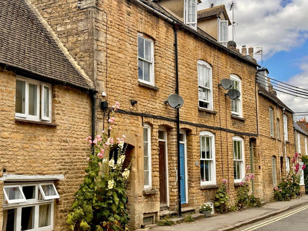 a brick building with windows and flowers on a street at Lamorna Cottage in Chipping Norton