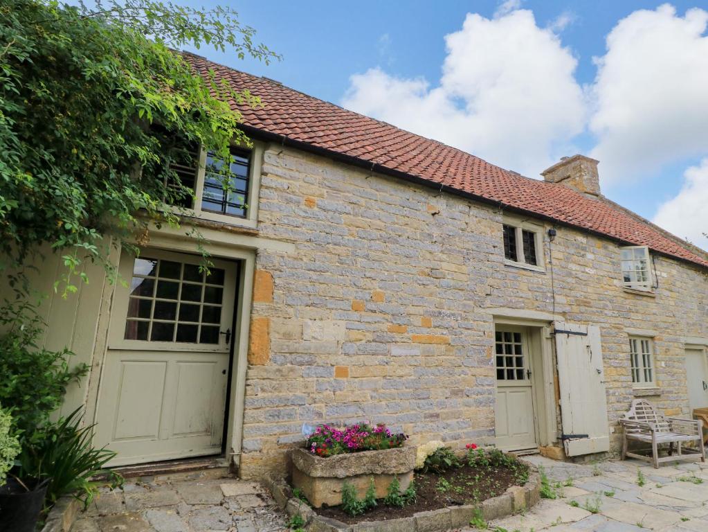 a brick house with two garage doors and flowers at The Farmhouse in Langport