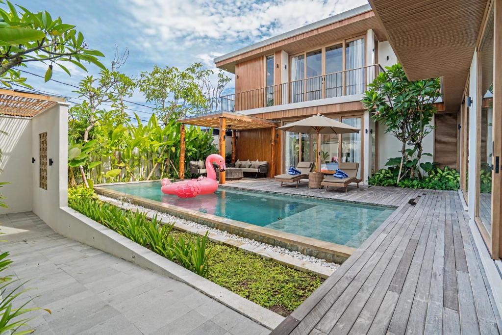 a swimming pool in a house with a pink inflatable pool noodle in front at Casa de Rua Villas in Badung