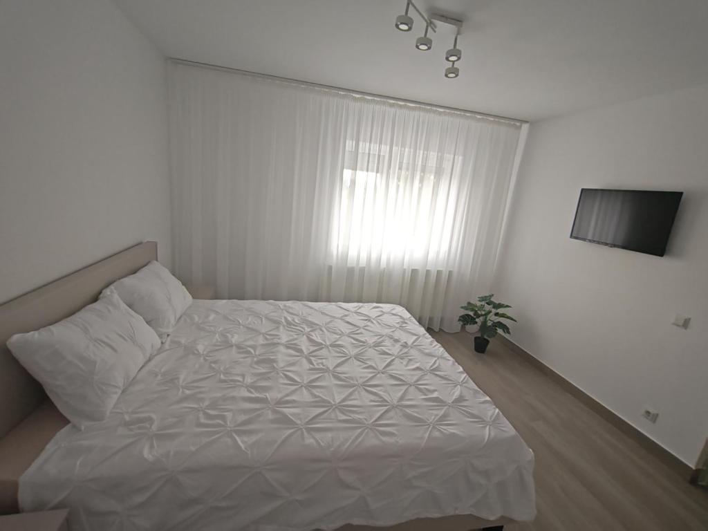 a white bedroom with a bed and a window at Apartament Bianco in Brăila