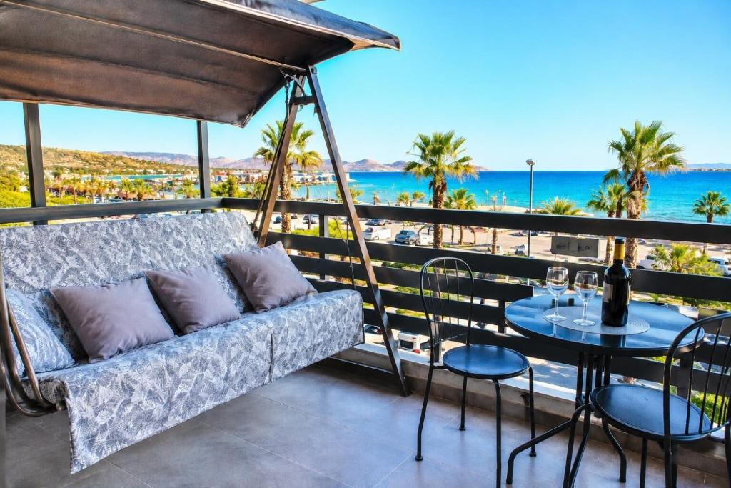 a couch on a balcony with a table and chairs at Varkiza Riviera Studio by the Sea in Varkiza