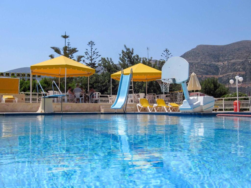 a large swimming pool with chairs and umbrellas at Stalis Bay Villa in Stalís