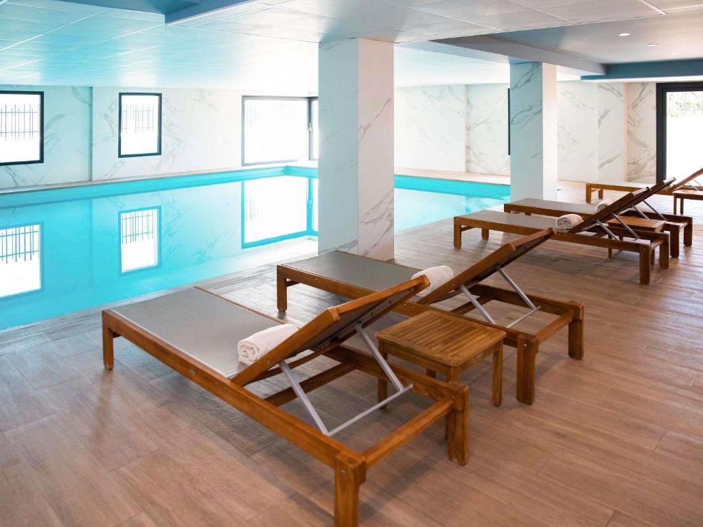a room with four chairs and a swimming pool at Mercure Hotel & Spa Bastia Biguglia in Biguglia