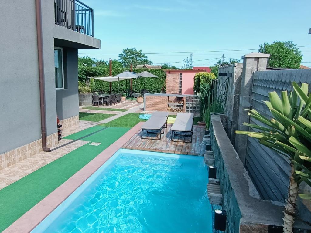 a small swimming pool with two lounge chairs in a backyard at Portofino Villa in Costinesti