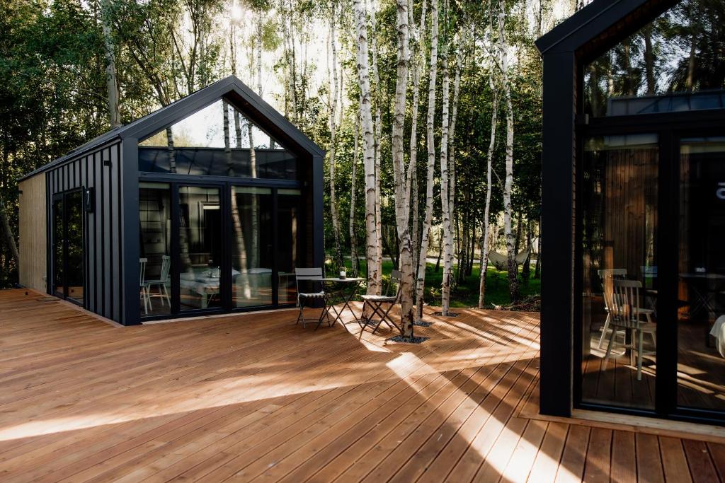 a black house on a wooden deck with trees at avocado domki in Kuśnie