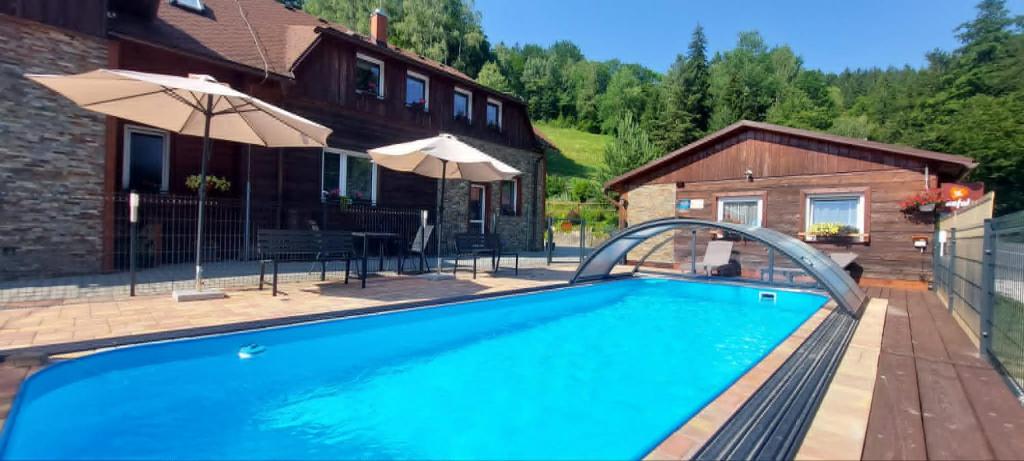 a swimming pool in front of a house at U Veselé lišky in Hutisko