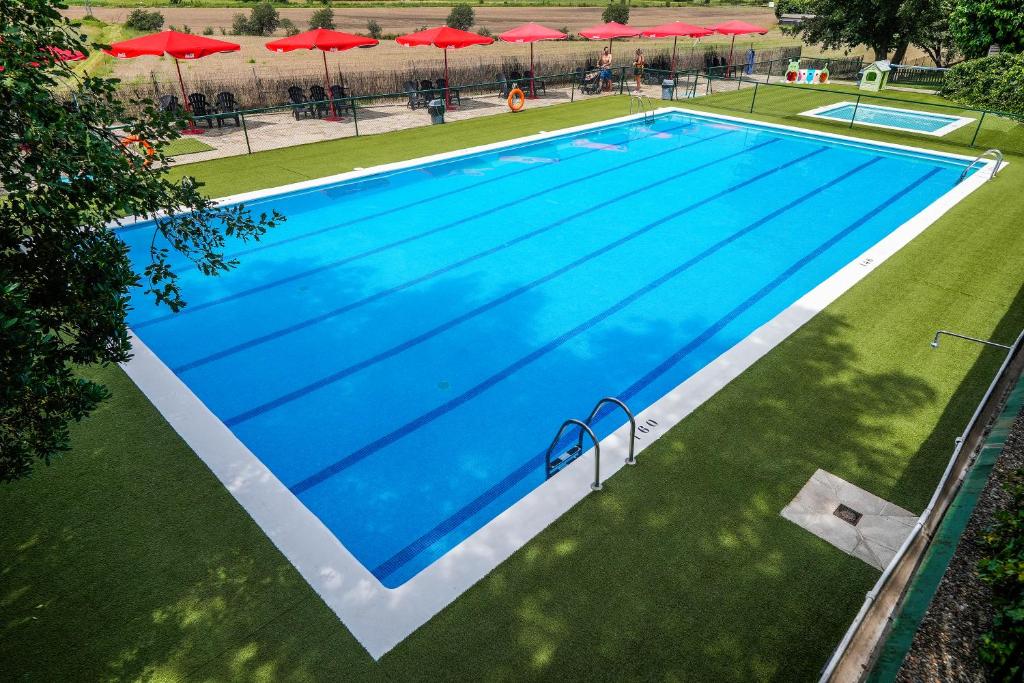 an overhead view of a large swimming pool with red umbrellas at HolaCamp Aínsa in Aínsa