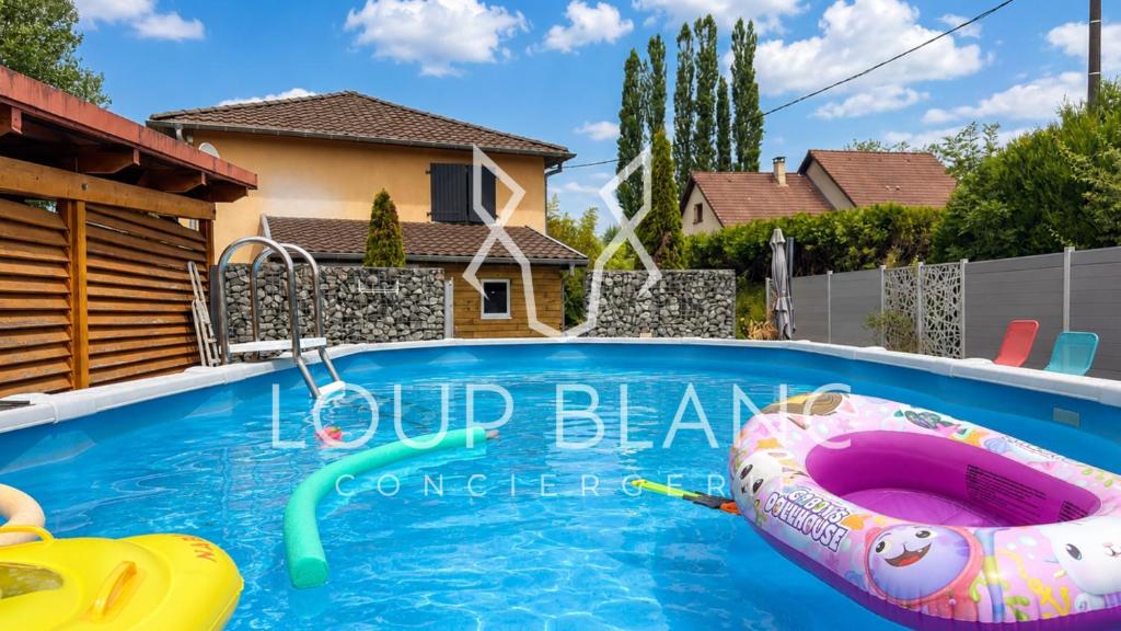 a swimming pool with an inflatable boat in a house at Piscine et pétanque - Calme proche Belfort in Châlonvillars