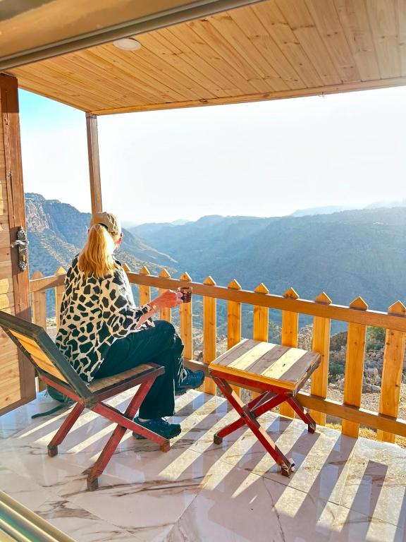 Eine Frau sitzt auf einem Stuhl auf einem Balkon mit Aussicht in der Unterkunft Dana Tower Hotel in Dana