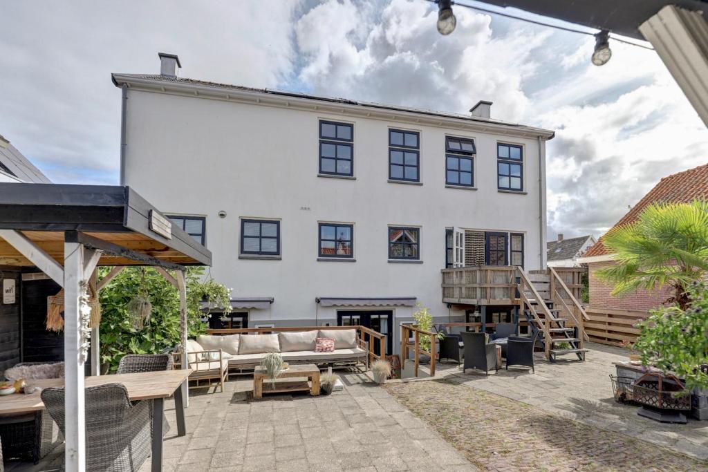 a large white house with a patio with a couch at By Onzz in Kamperland