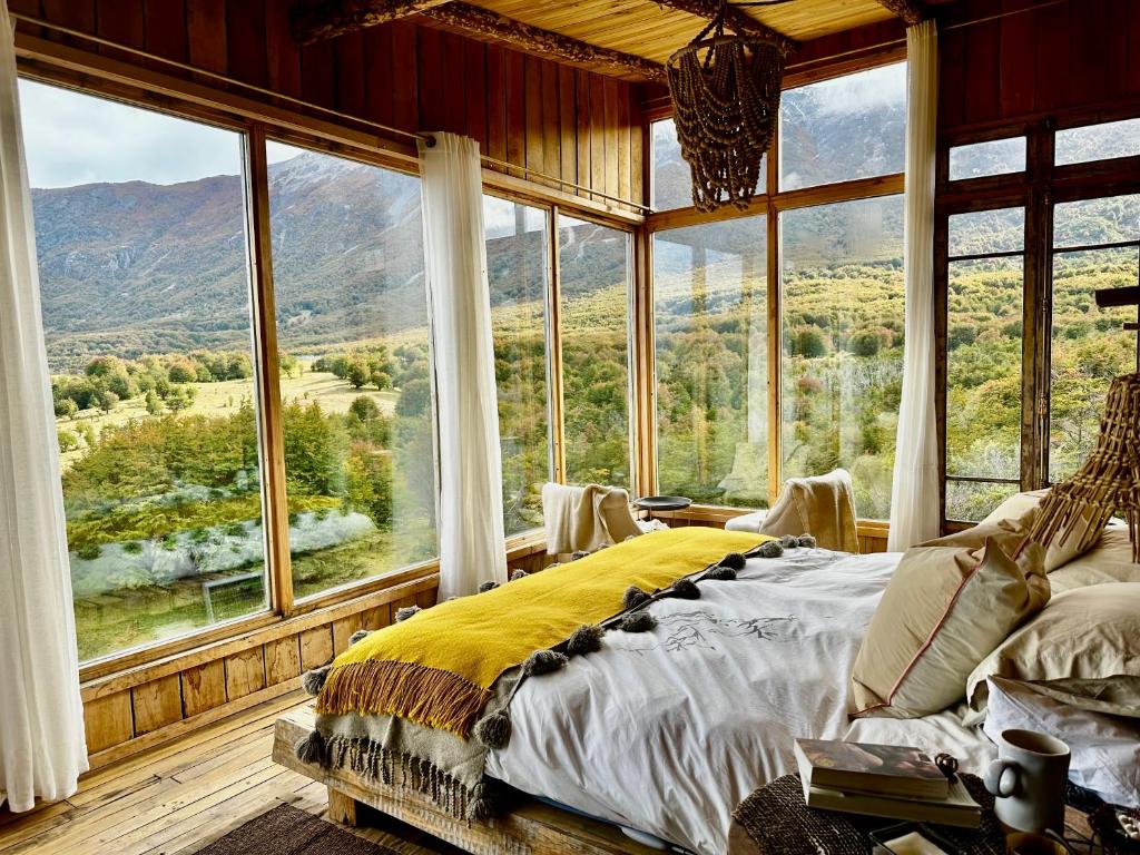 a bedroom with a bed in a room with large windows at Alto Castillo Lodge in Villa Cerro Castillo