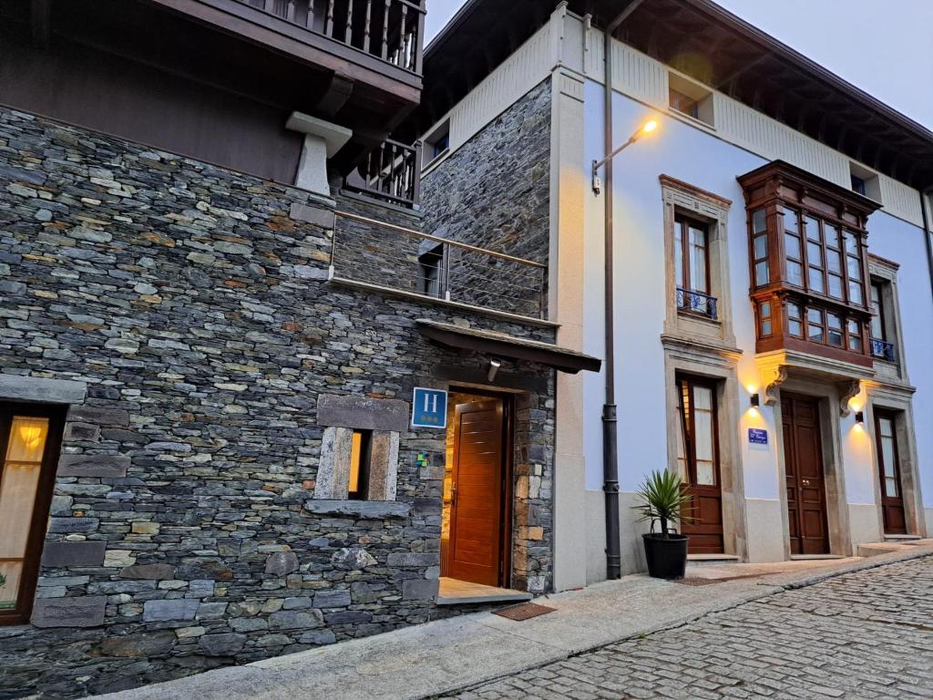 a building with a stone wall and a street at Casona El Gurugu in Luarca