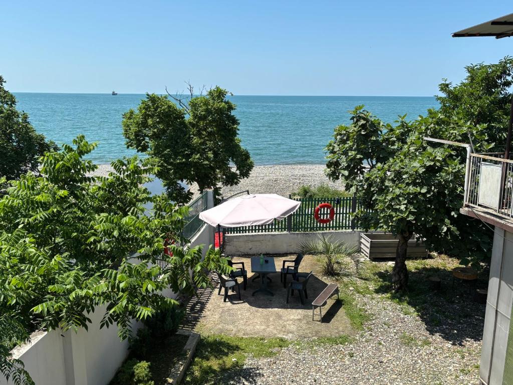 a patio with a table and an umbrella and the beach at Kety House in Makhinjauri