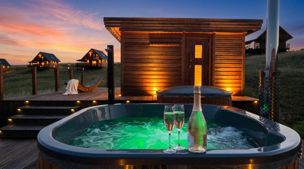 a hot tub with two glasses and a bottle of champagne at Jotwingia - Domki z Widokiem in Stare Juchy