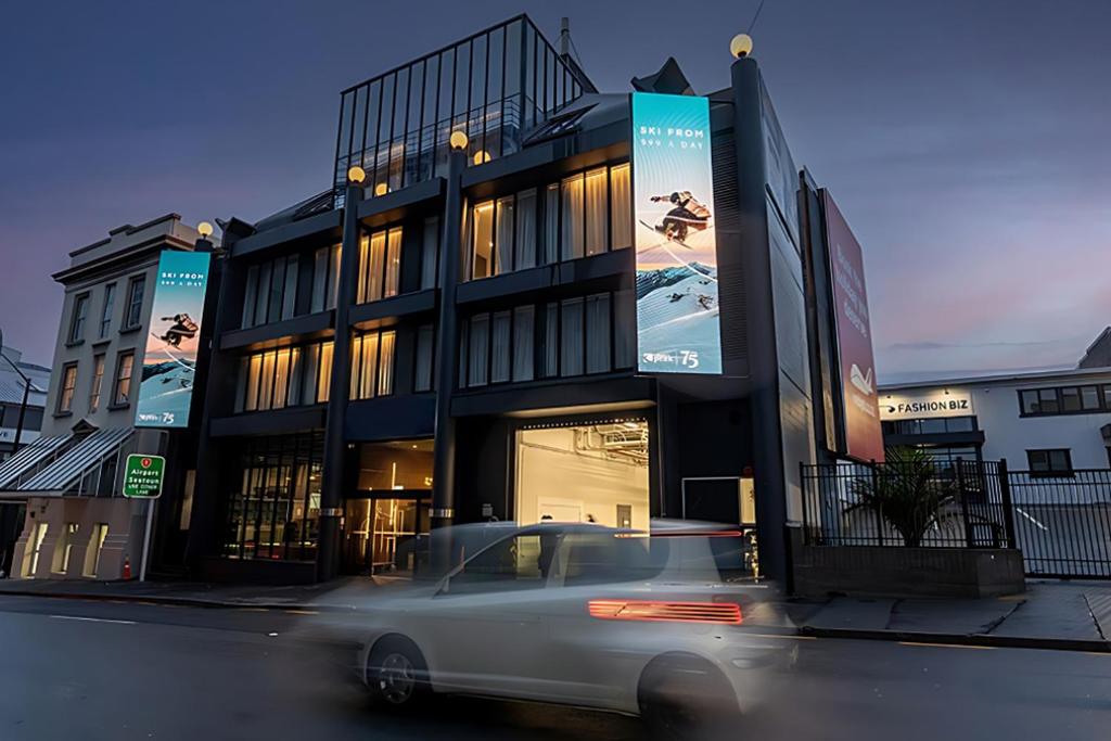 a white car driving in front of a building at The Viv Hotel Wellington in Wellington