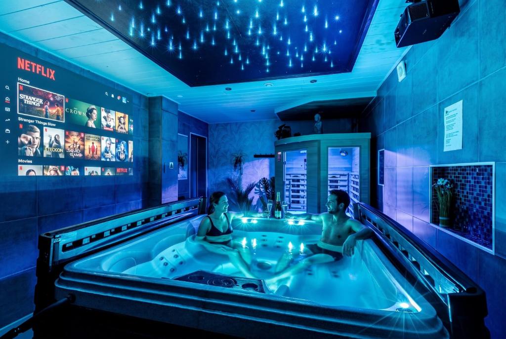 two women sitting in a jacuzzi tub in a room at Villa Cerf - SPA Privé, Climatisation, Sauna, Borne d'arcade, Babyfoot in Ittenheim