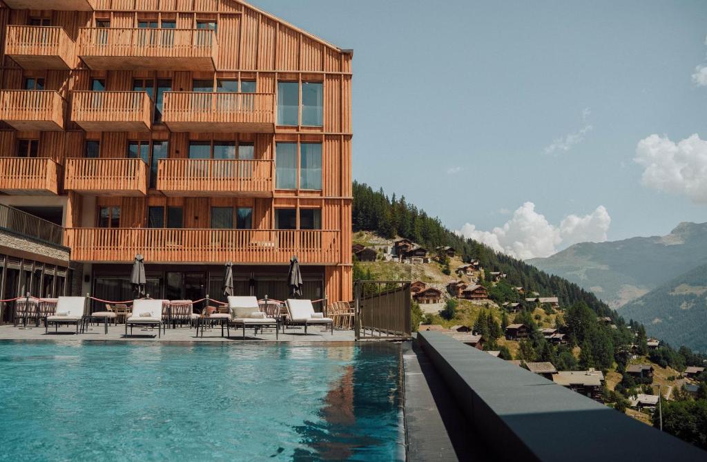 a hotel with a swimming pool in front of a building at Guernerés & Spa by Alpine Resorts in Grimentz