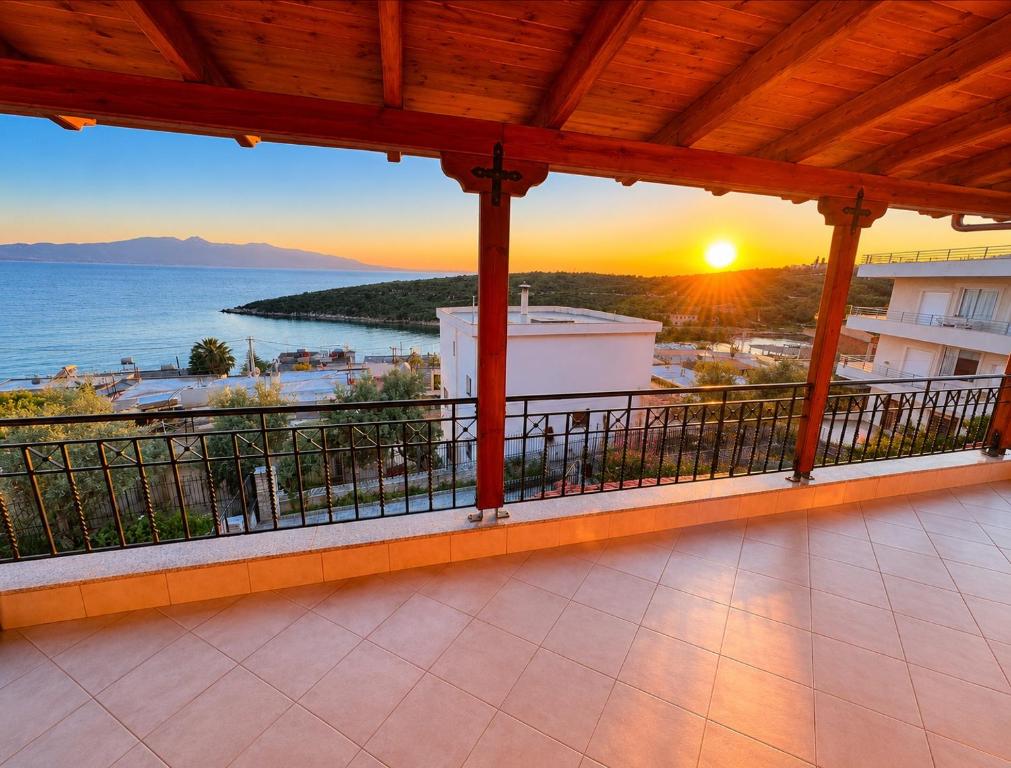 a balcony with a view of the ocean at sunset at Portside Living in Sarandë