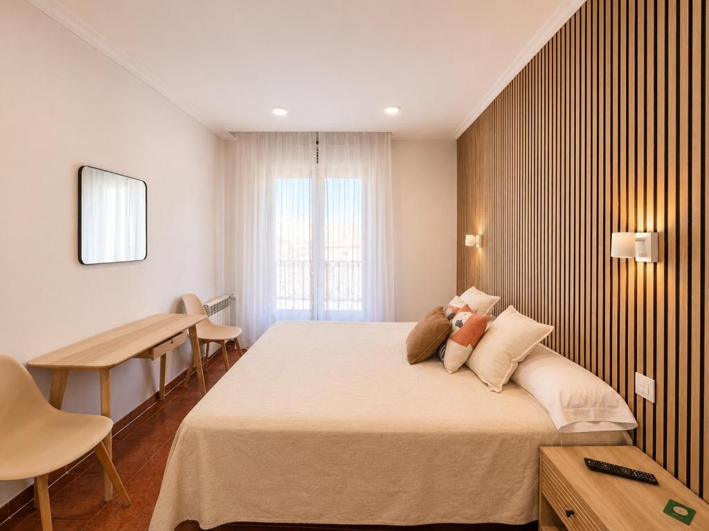 a hotel room with a large bed and a table at Hostal Bellas in Ávila