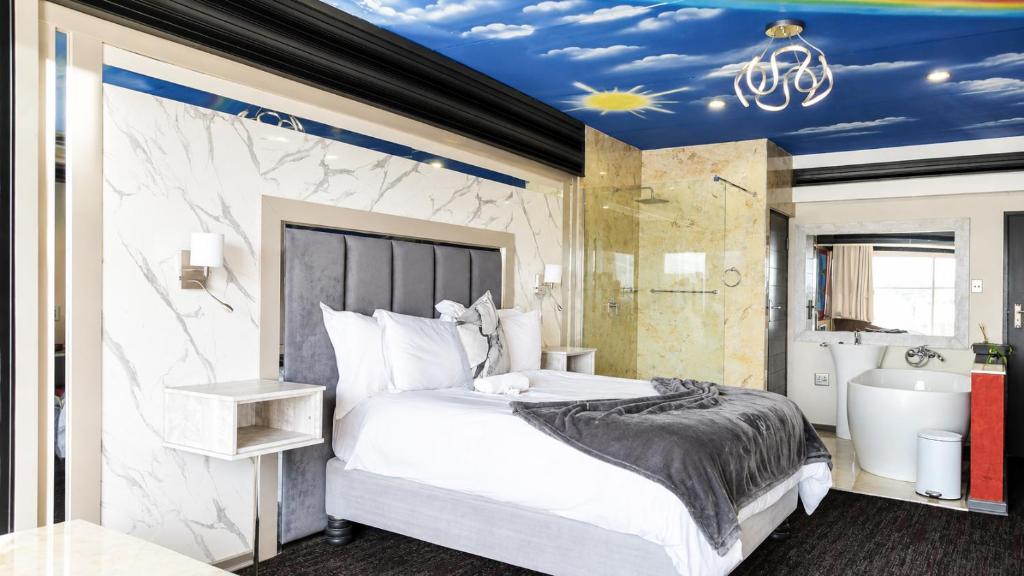 a bedroom with a king sized bed and a bathroom at Nkandla Lifestyle in Mthatha