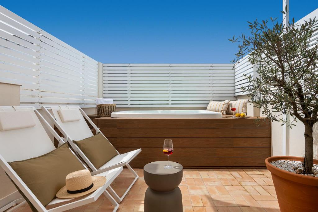 a patio with a tub and a chair and a glass of wine at Alameda 1851 - Private jacuzzi in Seville