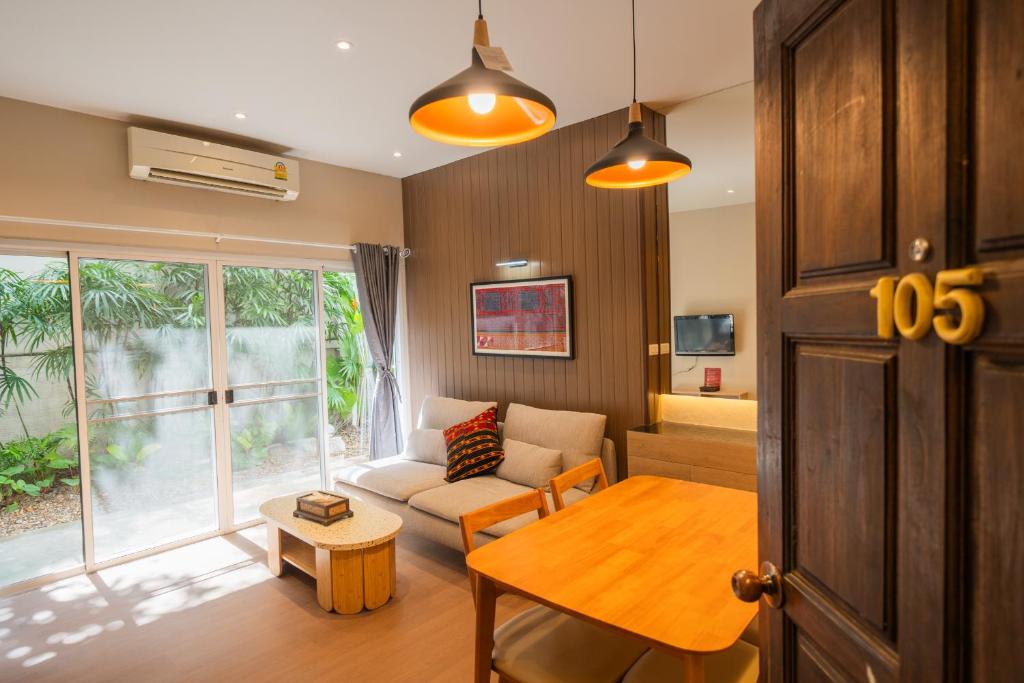 A doorway view shows the living room with a dining table, sofa and garden-facing doors.