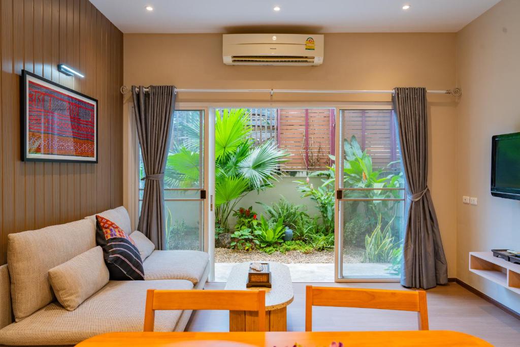 A bright living room combines a sofa, dining table, television and garden-facing glass doors.