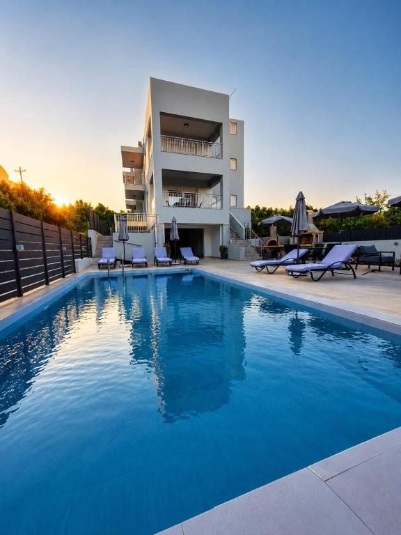 a large blue swimming pool in front of a building at Our Villa - Villa Rena in Rethymno