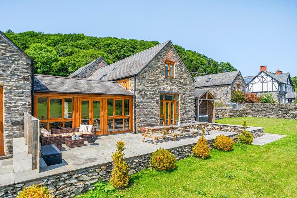 a stone house with a patio and a yard at The Barn in Corwen