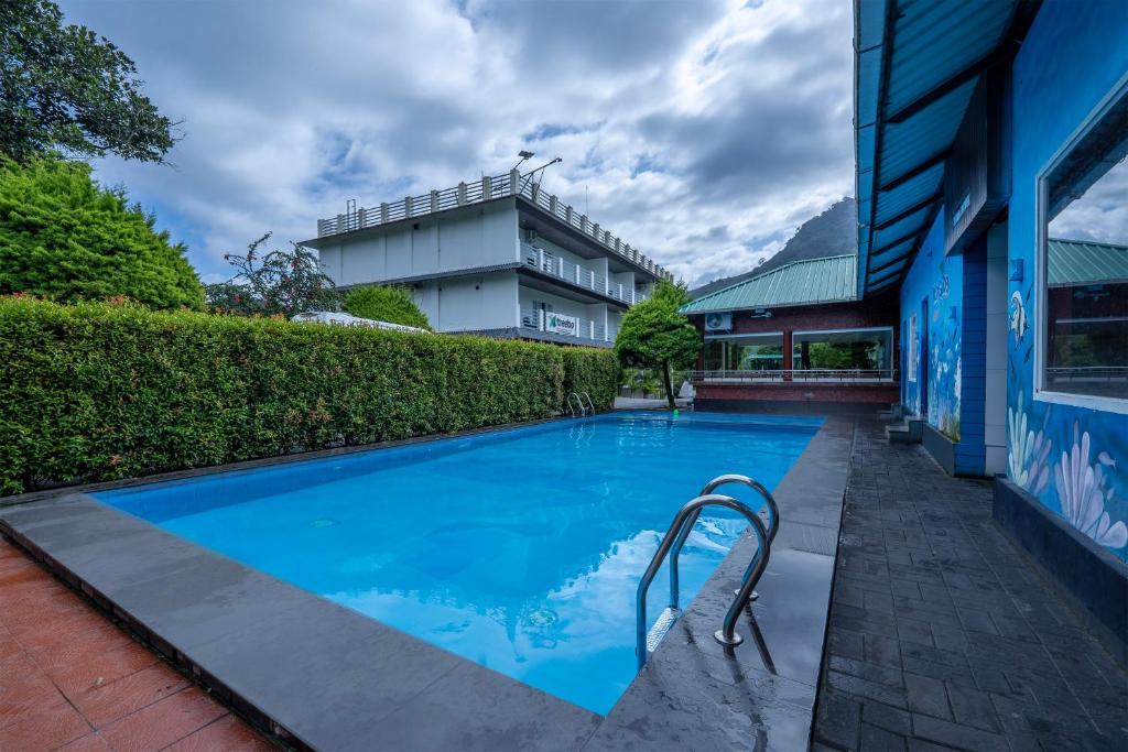a large blue swimming pool next to a building at Treebo Misty Garden Resort & Spa With Swimming Pool in Munnar