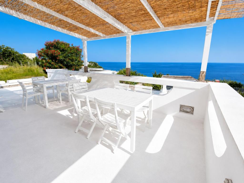 a white patio with white tables and chairs and the ocean at Maridea - Ondine in Ponza
