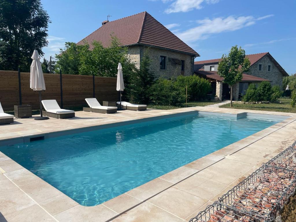 a swimming pool with chairs and umbrellas in a yard at Le Domaine Du Clos in Tourmont