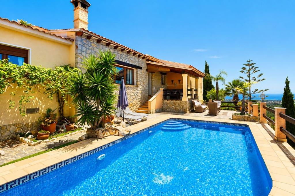 a villa with a swimming pool in front of a house at Cozy vacation home in Alfaz del Pi