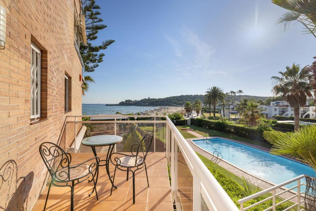 a balcony with a table and chairs and a swimming pool at Mora Beach in Tarragona
