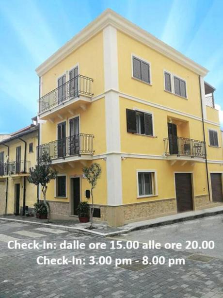 a large yellow building with balconies on a street at Scilla Resort in Scilla