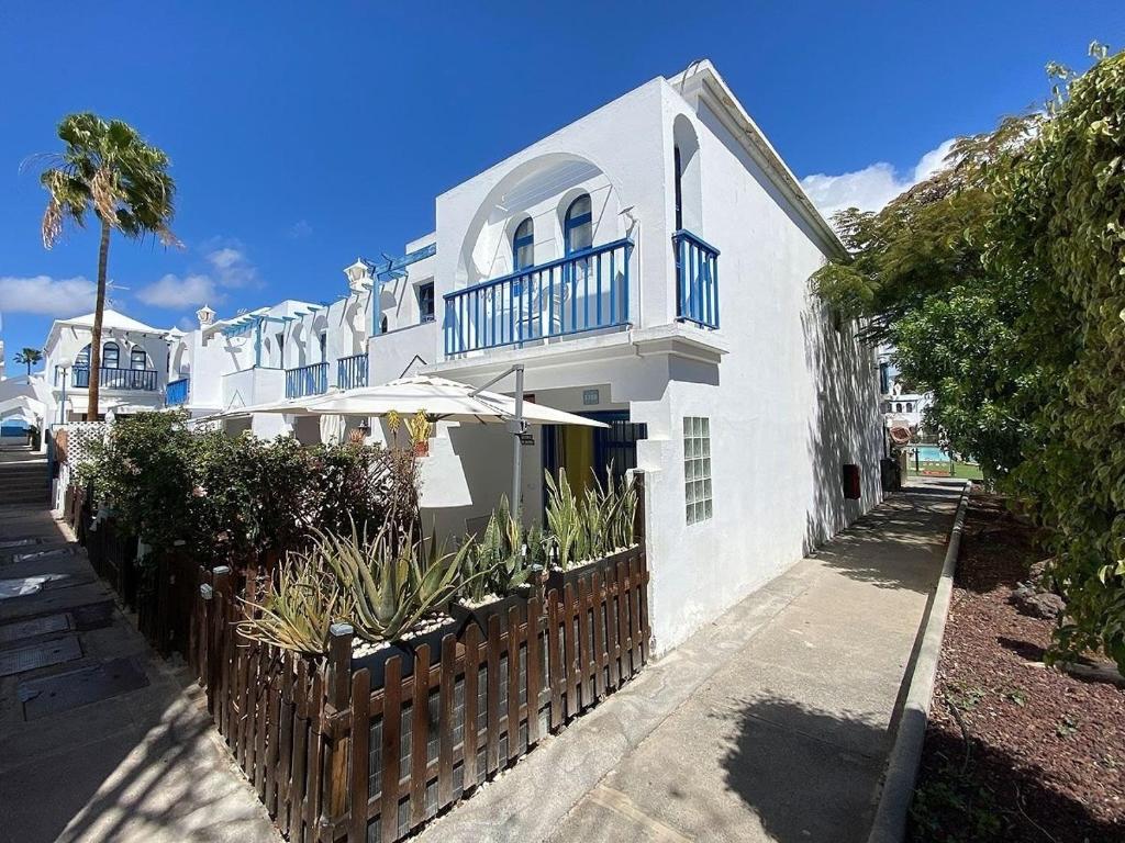 a white house with a fence and an umbrella at PLAYMAR Refugio Palmeras in Maspalomas