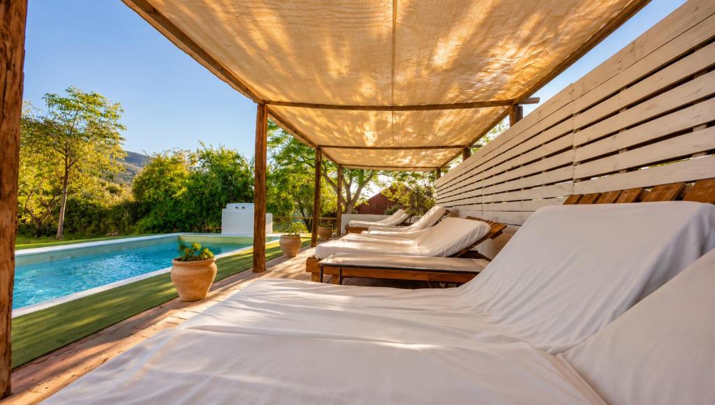 two beds on a patio with a swimming pool at Hotel Finca Aldabra in Pinos Genil