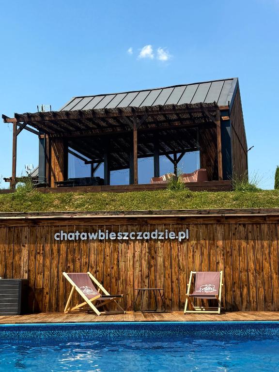 two chairs sitting next to a swimming pool at Stodoły w Bieszczadzie domy SPA z basenem i widokiem na góry in Polańczyk