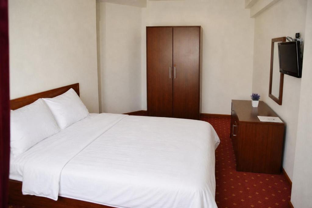 a bedroom with a white bed and a wooden cabinet at Sultan Otel Mardin in Sultan Koyu