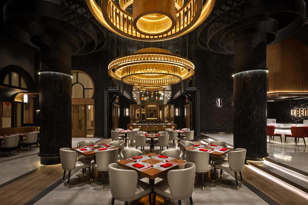 a restaurant with tables and chairs and a chandelier at Oaks Ibn Battuta Gate Dubai in Dubai